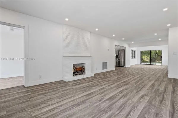 a view of empty room with fireplace and wooden floor