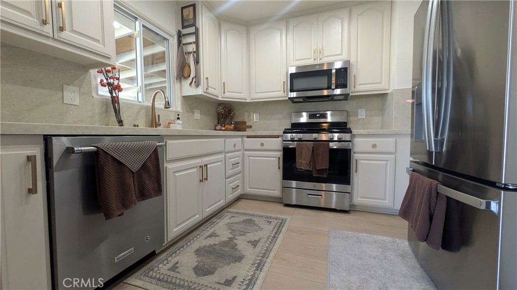 a kitchen with stainless steel appliances granite countertop a stove a refrigerator and a microwave