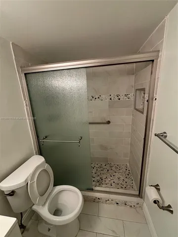 a bathroom with a granite countertop toilet a sink and a shower