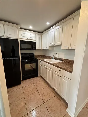 a kitchen with a sink a refrigerator and cabinets