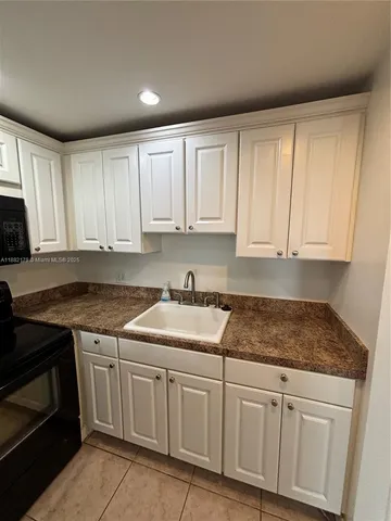 a kitchen with granite countertop white cabinets and stainless steel appliances