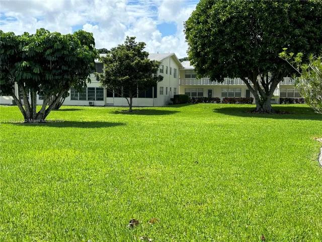 a front view of a house with garden and trees