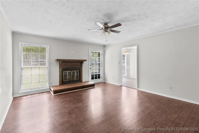 an empty room with wooden floor fireplace and windows