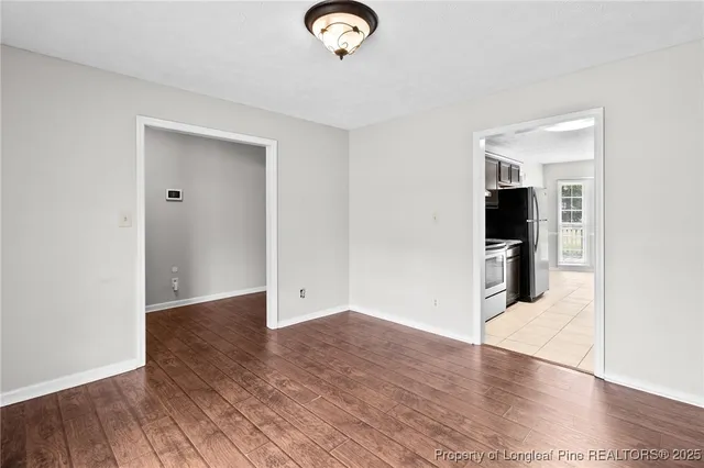 an empty room with wooden floor mirror and windows