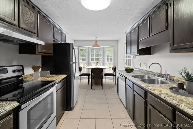 a kitchen with stainless steel appliances granite countertop a sink stove microwave refrigerator and cabinets
