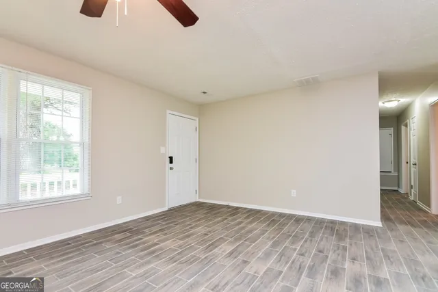 a view of an empty room with wooden floor and a window