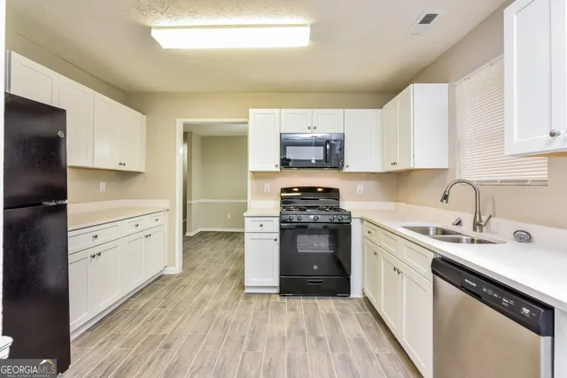 a kitchen with stainless steel appliances a sink cabinets and wooden floor
