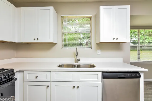 a kitchen with white cabinets and a window