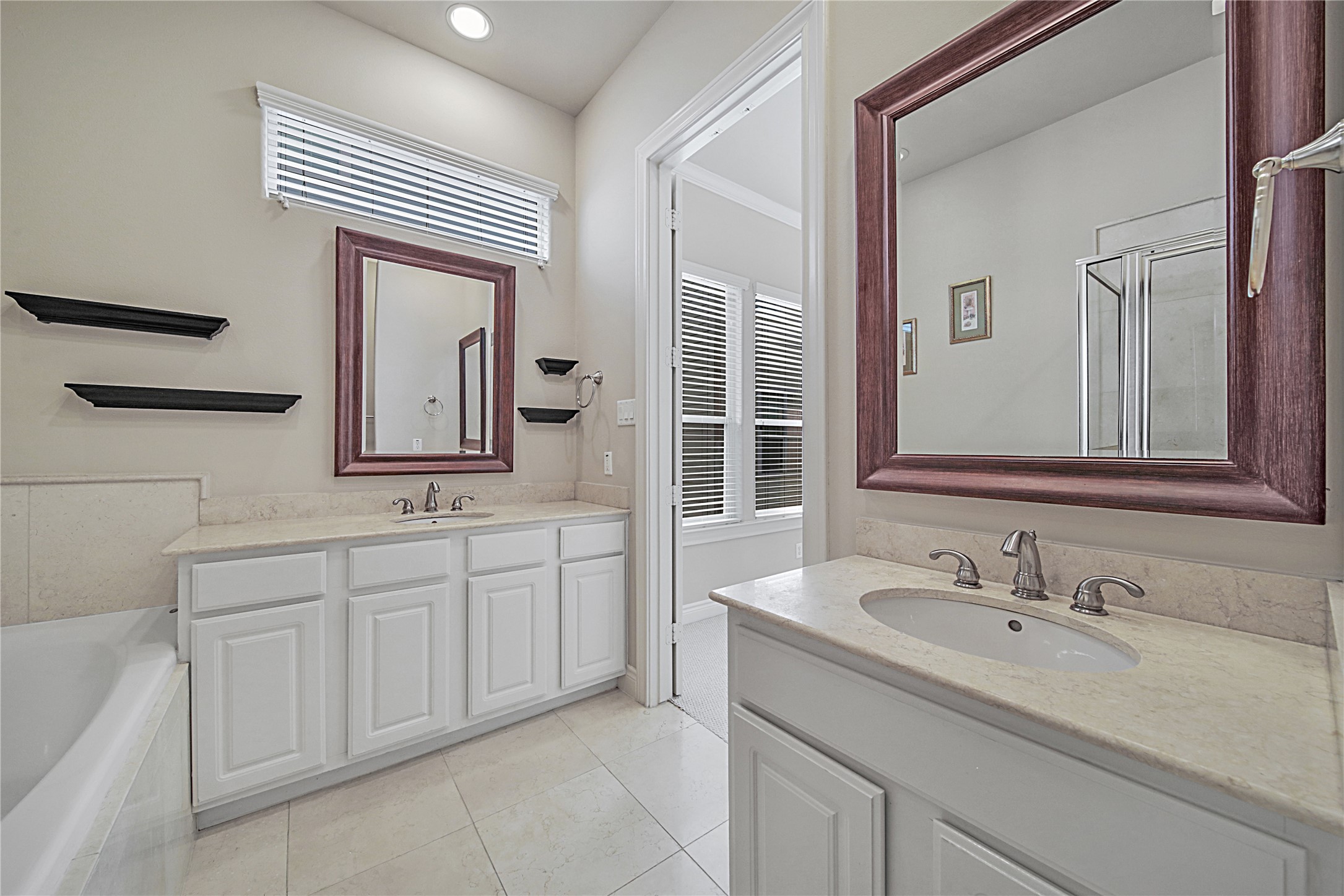 2726 Sherwin Street Houston, TX 77007 - Photo 13 of 23 The primary bathroom features a dual-sink vanity with elegant framed mirrors, a soaking tub, and modern fixtures. The neutral color palette and natural light create a bright, inviting space.