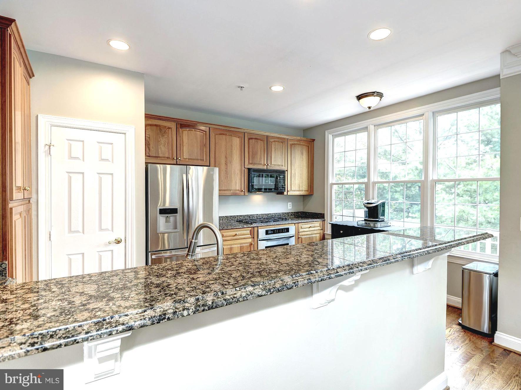 11400 Log Ridge Drive Fairfax, VA 22030 - Photo 14 of 30 a kitchen with stainless steel appliances granite countertop sink stove refrigerator and cabinets