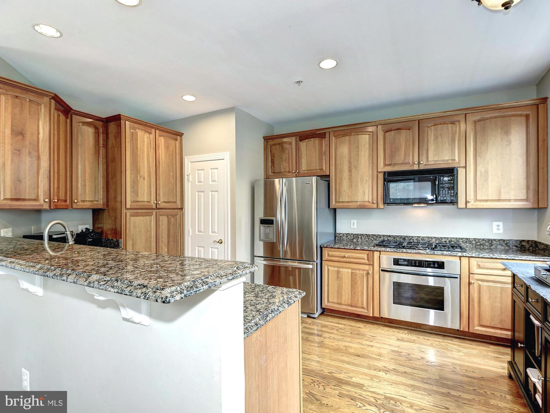 11400 Log Ridge Drive Fairfax, VA 22030 - Photo 4 of 30 a kitchen with kitchen island granite countertop a stove a sink and a refrigerator