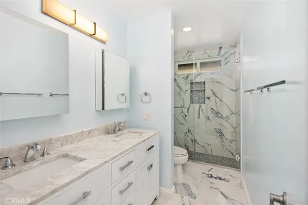 a bathroom with a granite countertop sink toilet and shower
