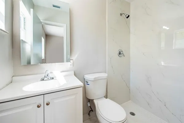 a bathroom with a sink a toilet a mirror and shower