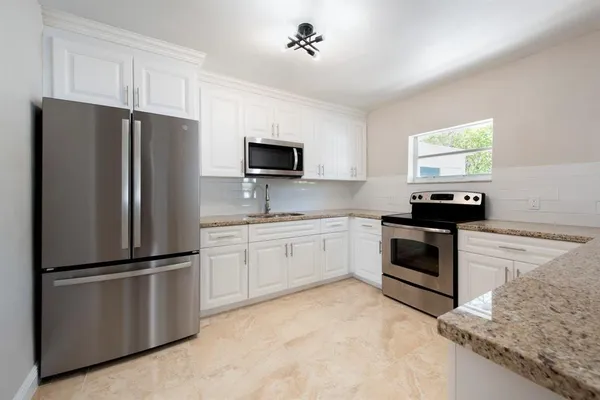 a kitchen with stainless steel appliances granite countertop a refrigerator sink and stove
