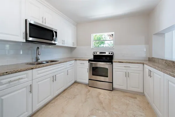 a kitchen with white cabinets appliances and a sink