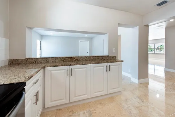 a bathroom with a granite countertop sink and white cabinets