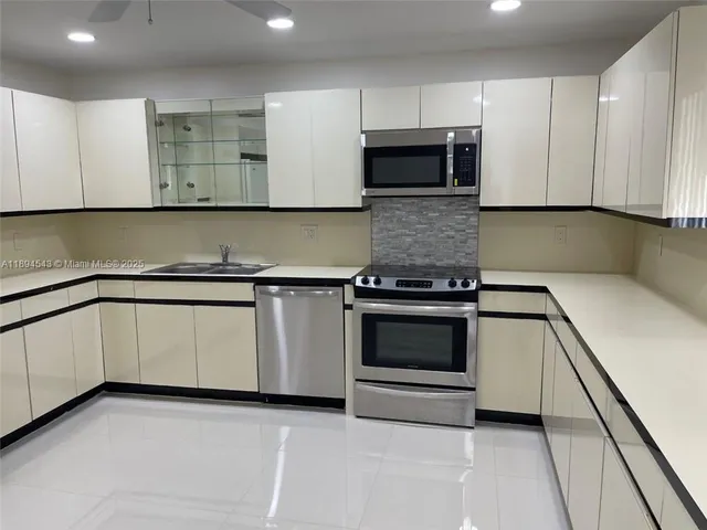 a kitchen with granite countertop white cabinets and stainless steel appliances