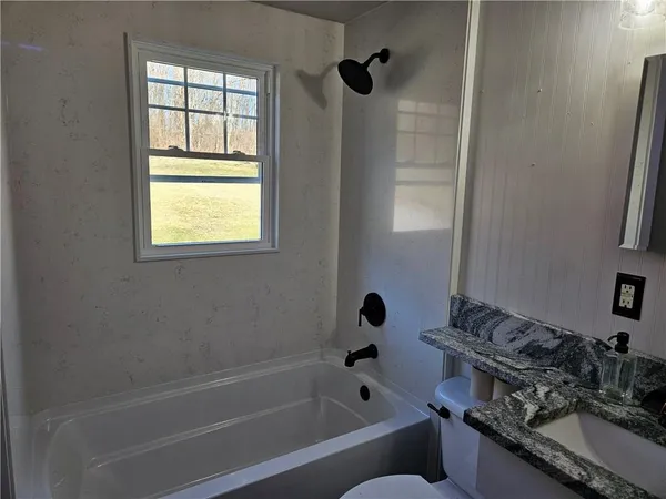 a bathroom with a tub a sink a window and a shower