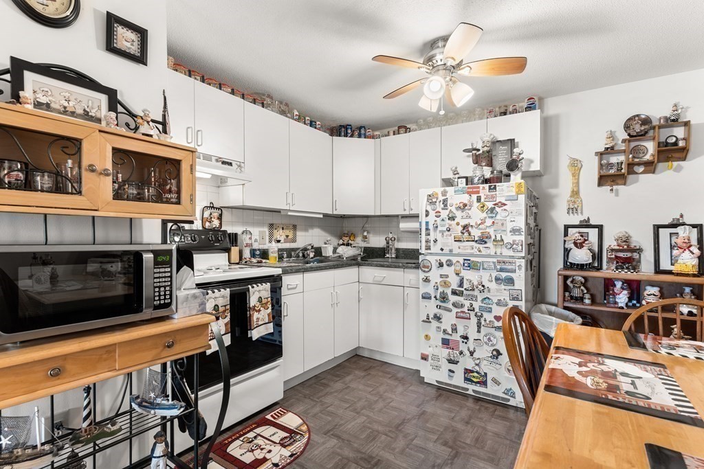 18 Woodman Way, Unit 17 Newburyport, MA 01950 - Photo 5 of 24 a kitchen with stainless steel appliances kitchen island granite countertop a stove a sink and a microwave