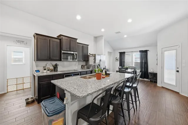 a view of kitchen with granite countertop refrigerator stove dining table and chairs