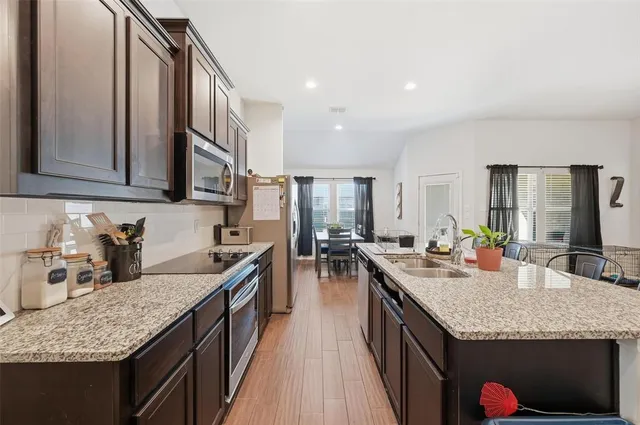 a kitchen with granite countertop kitchen island stainless steel appliances a sink stove and cabinets