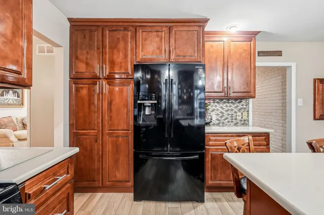 a kitchen with stainless steel appliances granite countertop a refrigerator a stove and a sink with wooden cabinets