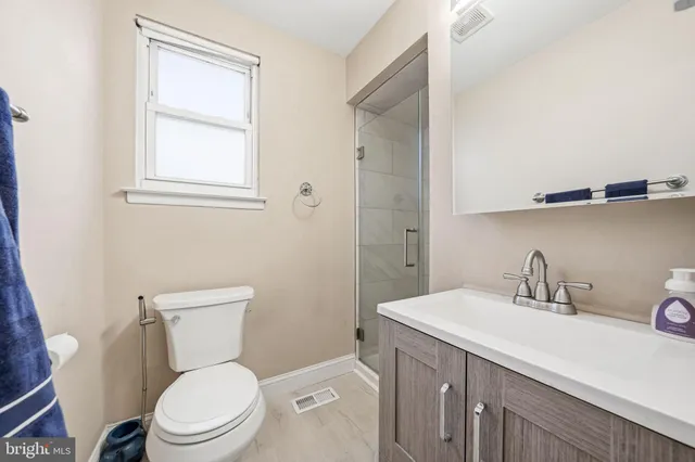 a bathroom with a toilet a sink a mirror and a window