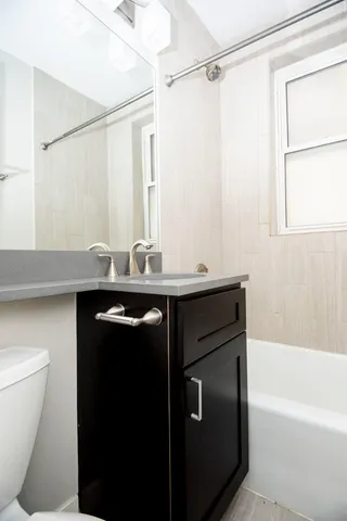 a bathroom with a granite countertop sink a toilet and shower