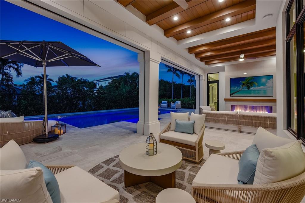 529 Neapolitan Way Naples, FL 34103 - Photo 9 of 26 a living room with patio furniture and a floor to ceiling window