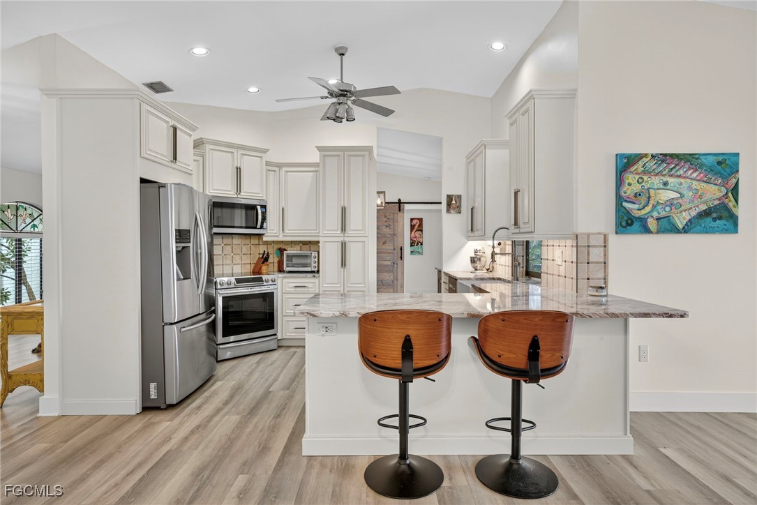 1823 Stevenson Road North Fort Myers, FL 33917 - Photo 4 of 32 a kitchen with stainless steel appliances a dining table chairs sink and stove top oven
