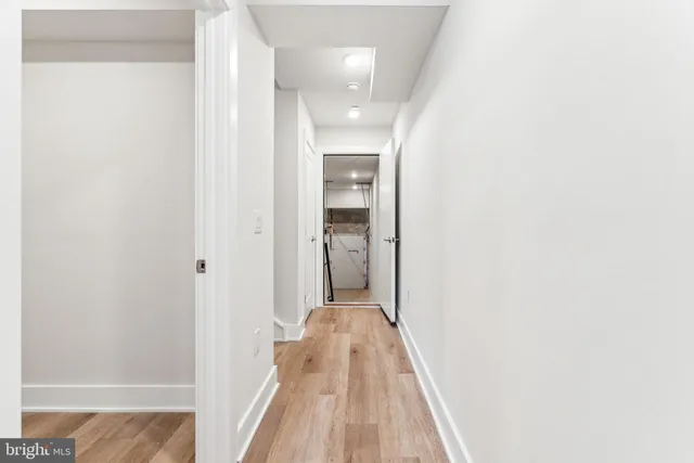 a view of a hallway with wooden floor and a bathroom