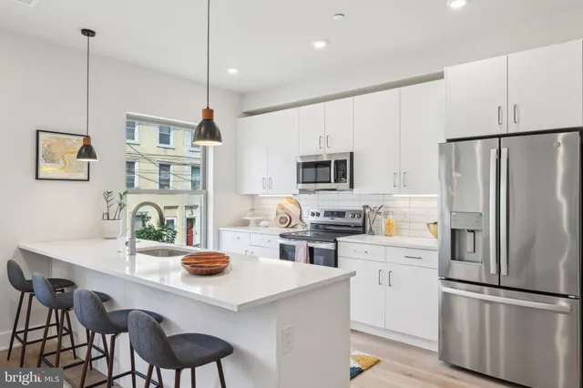 a kitchen with stainless steel appliances a refrigerator a sink a stove a table and chairs