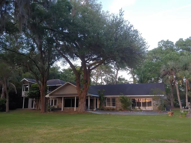 a front view of a house with garden and trees
