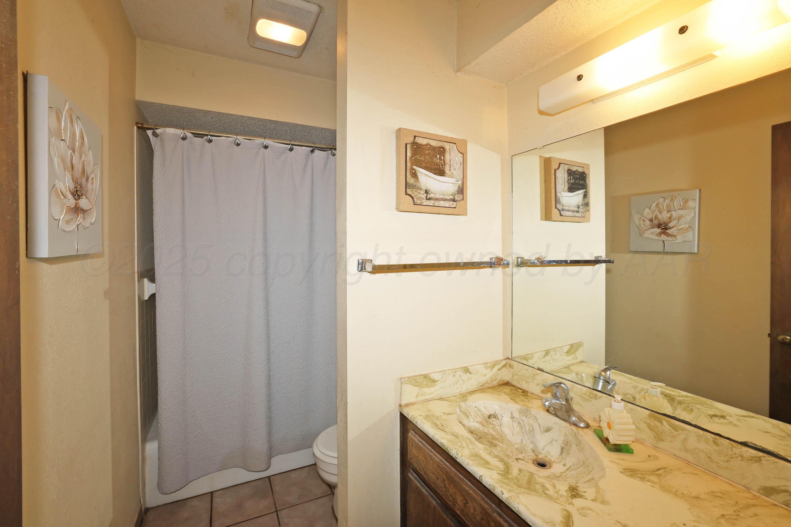 6225-6227 Belpree Road Amarillo, TX 79106 - Photo 14 of 31 a bathroom with a granite countertop sink a mirror and a shower