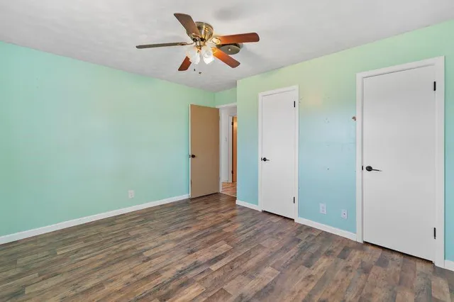an empty room with wooden floor and a ceiling fan