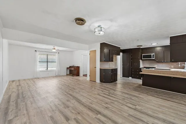 a large kitchen with stainless steel appliances wooden floor and a refrigerator
