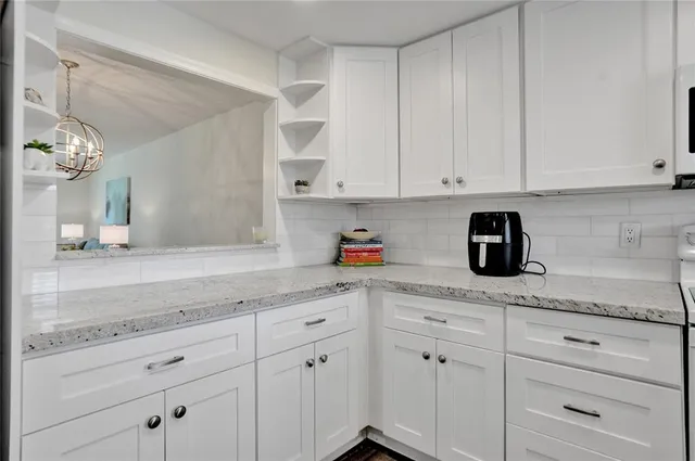 a kitchen with granite countertop white cabinets and white appliances