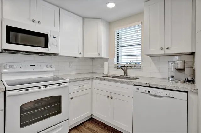 a kitchen with granite countertop white cabinets stainless steel appliances and sink