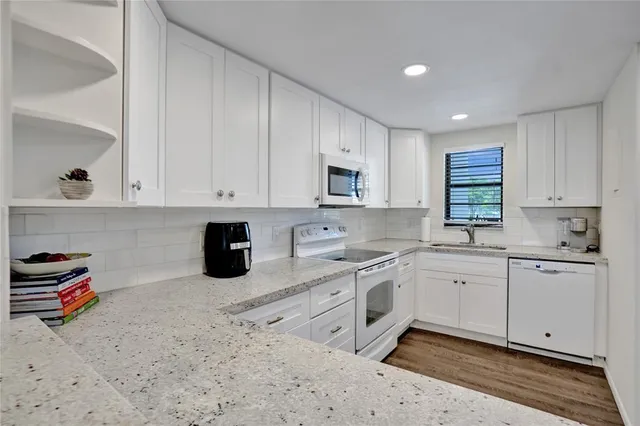 a kitchen with a sink white cabinets and a stove