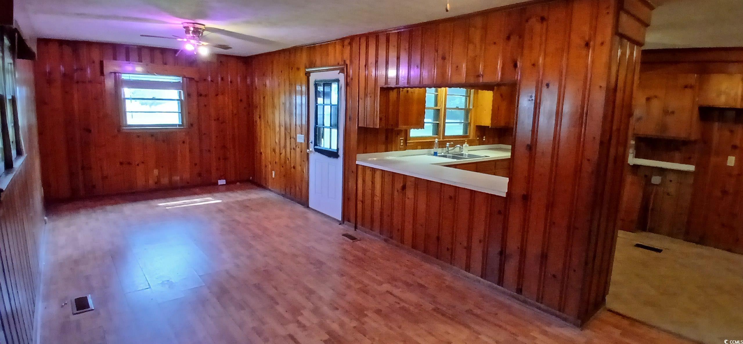 1206 French Road Mullins, SC 29574 - Photo 21 of 31 Kitchen with brown cabinets, ceiling fan, light countertops, light wood-style floors, and wood walls