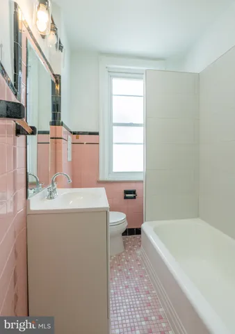 a bathroom with a granite countertop bathtub sink vanity mirror and toilet
