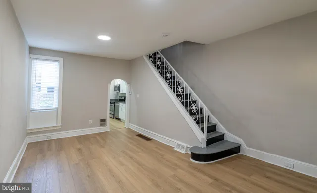 a view of an empty room with wooden floor and stairs