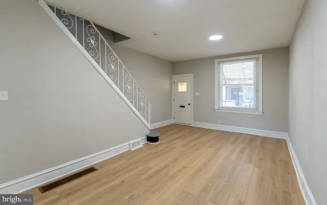 a view of empty room with wooden floor and fan
