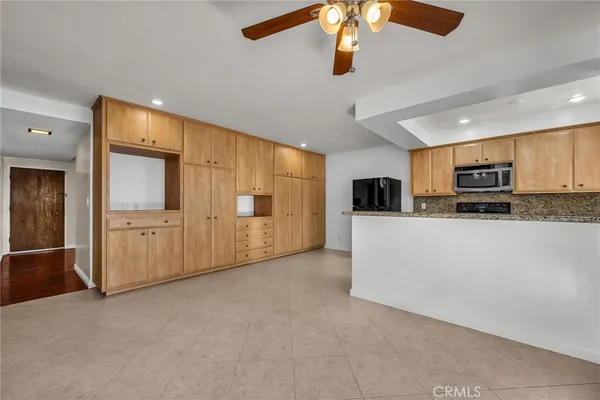 a view of a livingroom with furniture oven kitchen view and a chandelier fan