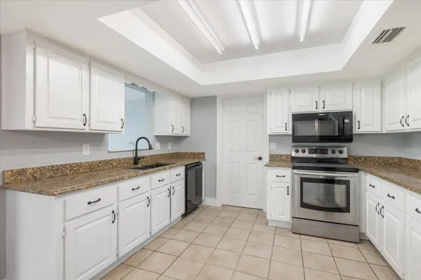 a kitchen with granite countertop white cabinets stainless steel appliances and a sink