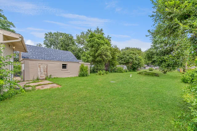 a backyard of a house with table and chairs plants and large tree