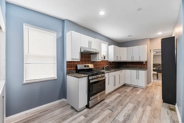 a kitchen with granite countertop white cabinets and wooden floor