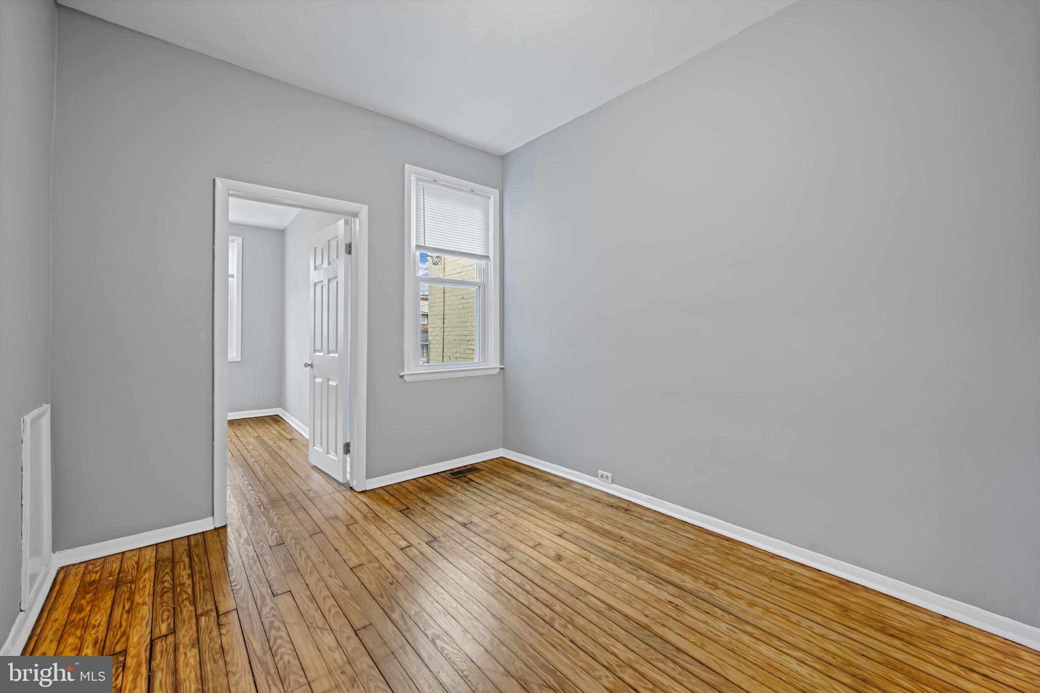 628 Savage Street Baltimore, MD 21224 - Photo 19 of 45 an empty room with wooden floor and windows