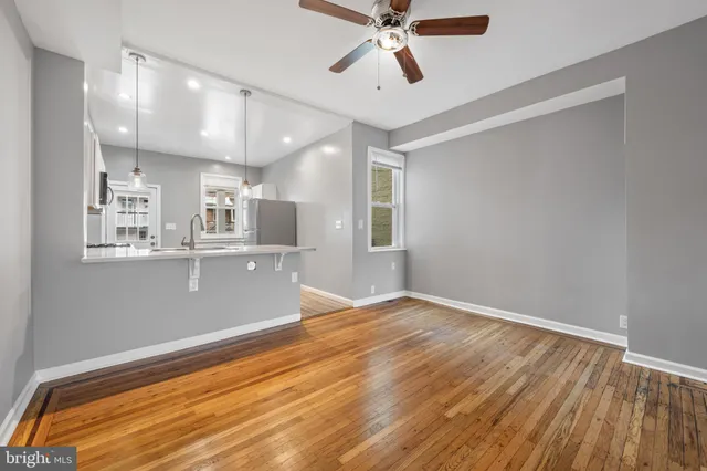 a view of empty room with wooden floor and fan