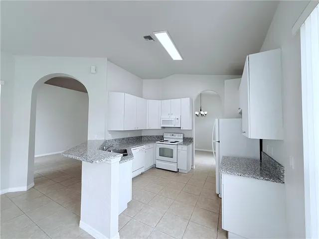 a kitchen with stainless steel appliances kitchen island granite countertop a sink a stove and a refrigerator